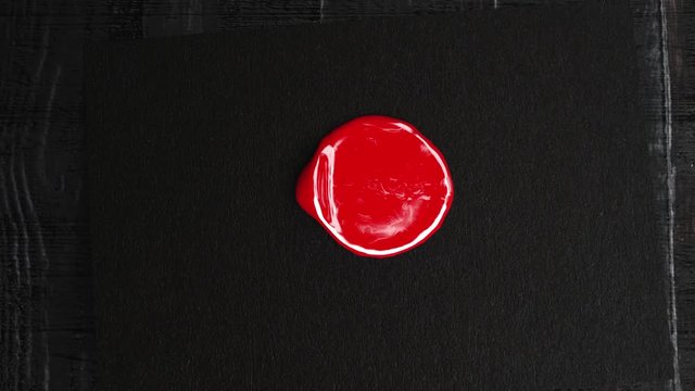 Red wax drop to black paper and golden stamp make a seal