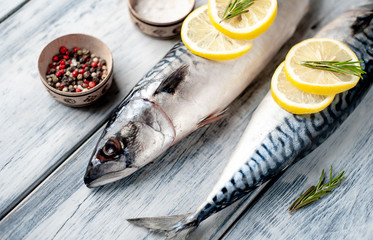 Fresh, raw mackerel with spices, tomatoes, rosemary on a wood background