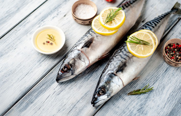 Fresh, raw mackerel with spices, tomatoes, rosemary on a wood background