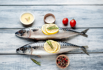 Fresh, raw mackerel with spices, tomatoes, rosemary on a wood background