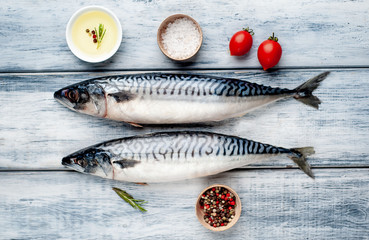 Fresh, raw mackerel with spices, tomatoes, rosemary on a wood background