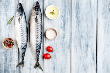 Fresh, raw mackerel with spices, tomatoes, rosemary on a wood background