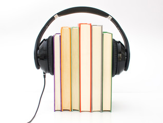 Audiobooks concept. Headphones put over book and white background.