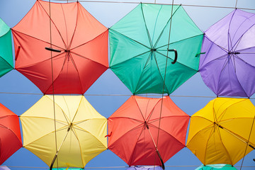 Background of multicolored umbrellas hanging against the blue sky.