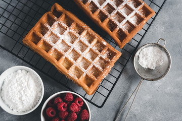 Homemade waffles with raspberries on grey table