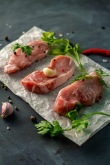 three fillet slices on a baking paper with spices and herbs on a black tables