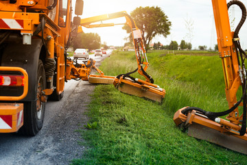 Professional industrial machine cutting grass by the road for traffic safety. Industrial grass...