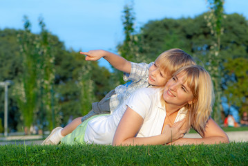 happy mother with her son on a glade in the park