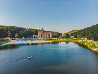 Fototapeta premium aerial view of resort near lake forest around. people on boats and catamarans