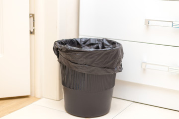 Black plastic basket in the office on the floor