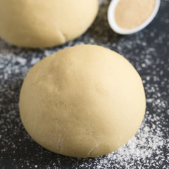 Risen or proved yeast dough balls for bread or pizza on a floured slate surface, photographed with natural light (Selective Focus, Focus on the front of the dough ball)