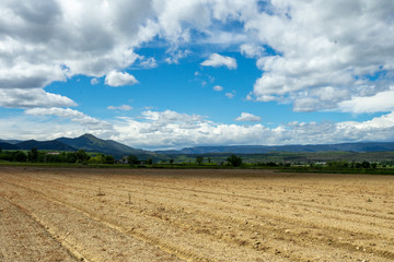 champs de terre labourée devant des montagnes