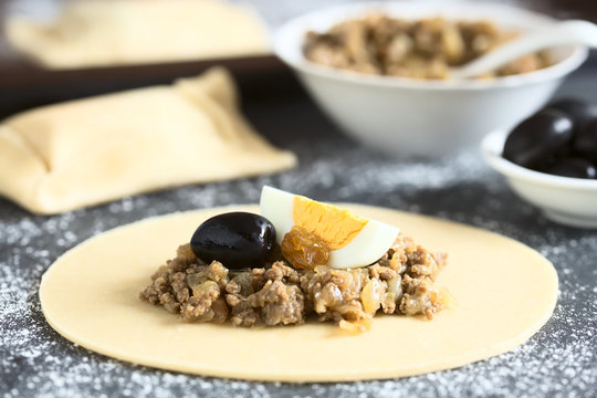 Zubereitung der chilenischen Empanada de Pino, ein herzhaftes Geb&auml;ck gef&uuml;llt mit Hackfleisch, Oliven, Rosinen und Ei (Selektiver Fokus, Fokus in die Mitte des Bildes)