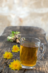 Dandelion tea background, herbal remedy. Dandelion tea, flower, leaves and root on wooden background.