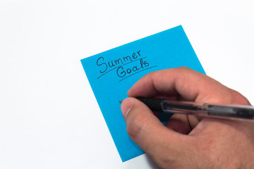 summer goals. hand holding a black pen writing down the plans for vacation