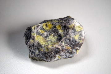 A sample of native sulfur in dolomite on a gray background. Origin: Guardak, Turkmenistan.