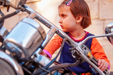 Naklejka premium Law for child drivers under 18 concept. Portrait of cute little biker child girl sitting on a motorcycle.