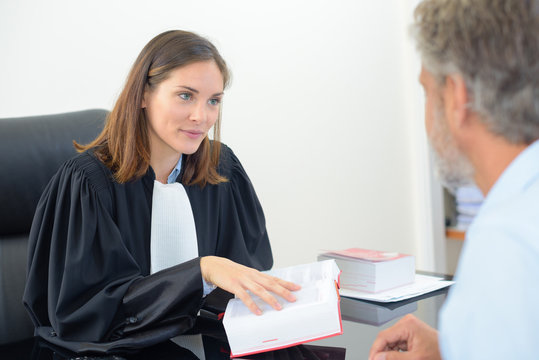female lawyer holding book in meeting with male client