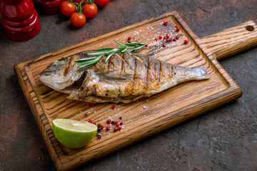 Dorado on grill on the board with rosemary and lime