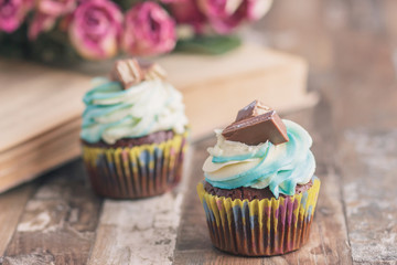 Handmade chocolate muffins with decorations. Book and a bouquet of roses