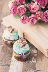 Handmade chocolate muffins with decorations. Book and a bouquet of roses