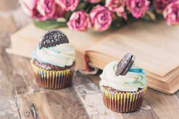 Handmade chocolate muffins with decorations. Book and a bouquet of roses