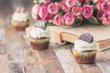Handmade chocolate muffins with decorations. Book and a bouquet of roses