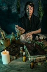 Dark Witch at work: black magic woman makes the witchery by mixing herbs, casting the spells, running magic rituals