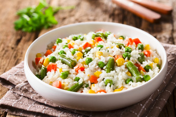 Cooked white rice mixed with colorful vegetables (onion, carrot, green peas, corn, green beans) in...