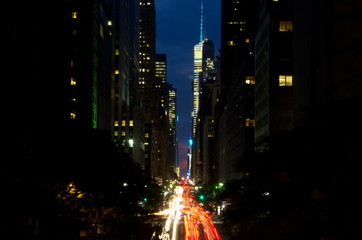 Obraz premium New York City street canyon at night, traffic motion light trails