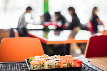 set of rolls from California and Philadelphia in the background of a cafe. Tasty European rolls on the background of people. people out of focus