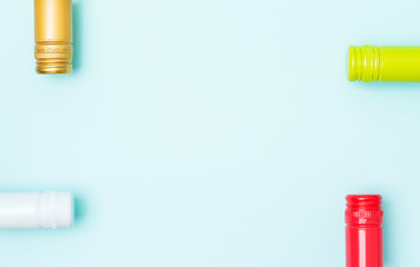 Screw bottle foil caps in different bright colors of white and rose wine bottles on blue background with copy space. Minimal abstract colorful mockup concept of alcohol beverage. Flat lay.