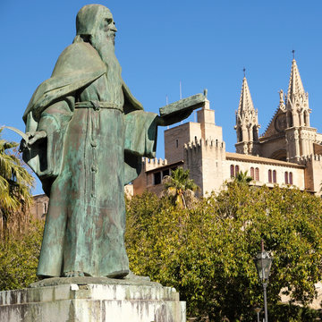 Side view of the famous gothic cathedral Santa Maria La Seu, the Kings palace Almudaina and statue of Ramon Llull in the foreground