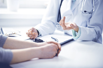Doctor and  female patient sitting at the desk and talking  in clinic near window. Medicine and...