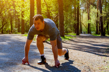 Determined Caucasian sprinter preparing to start racing on road in park