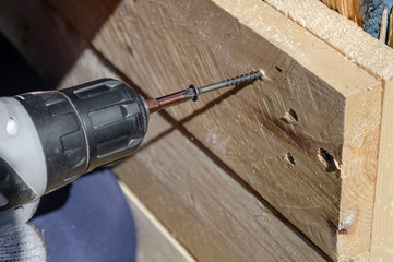 man drills the wood workpiece with a cordless drill