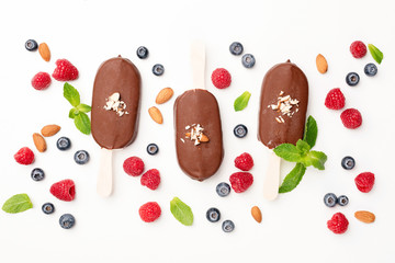 Chocolate ice cream pops and berries flat lay on white background. Table top view. Summer concept