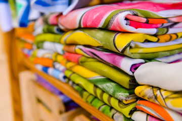 Fototapeta premium printed t-shirts folded on shelf, printed fabrics, clothing store, colorful clothing store, stacked laundry, folded clothes, colorful clothes, stacked clothes, colored background