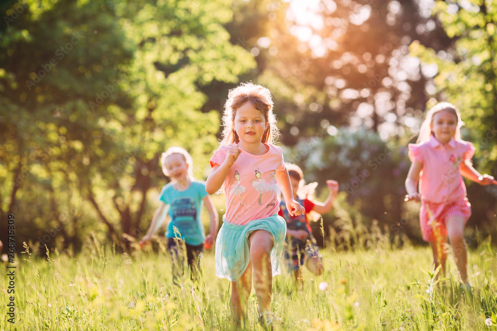 Wall mural large group of kids, friends boys and girls running in the park on sunny summer day in casual clothe