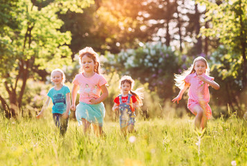 Fototapeta premium Large group of kids, friends boys and girls running in the park on sunny summer day in casual clothes .