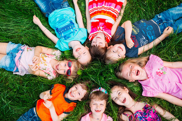 A group of children lying on the green grass in the Park. The interaction of the children.