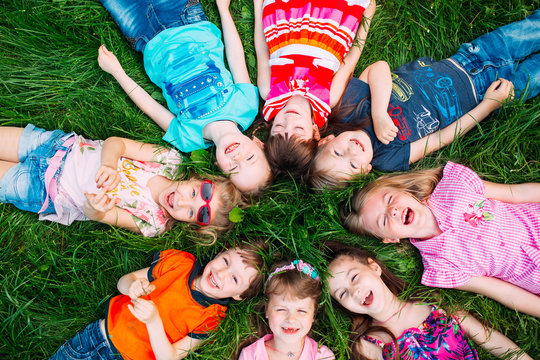 A group of children lying on the green grass in the Park. The interaction of the children.