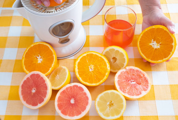 One people using squeezer for a mix of fruit juice for healthy breakfast or break. Freshness and vitamines from citrus, orange and grapefruit