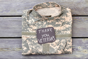 Veteran's camo jacket, top view. Thank you veterans, wooden background.