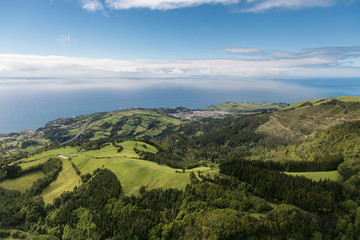 aerial landscape views on green hills, pastures and the ocean as seen from Lagoa do Fogo (Lake/ Lagoon of Fire) in direction to the south coast of Sao Miguel Island