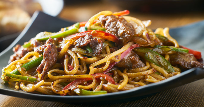 asian stir fried noodles with beef peppers and onions panorama