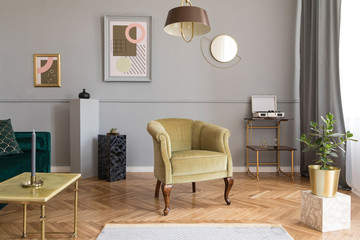 Stylish and tasty living room of apartment interior with elegant green velvet armchair and sofa, marble table, design lamp and chic accessories. Abstract paintings on the gray wall. Luxury home decor.
