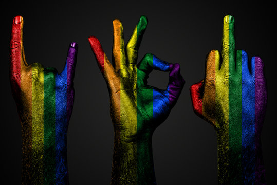 a set of three hands with a painted flag LGBT show middle finger, goat and Okay, a sign of aggression, protest and approval on a dark background. - Powered by Adobe