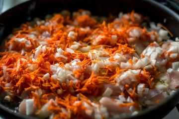 Cooking for soup, chopped carrots and onions are fried in a pan