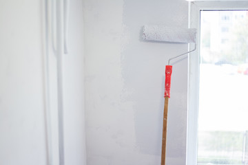 Close-up of paint roller on white wall background